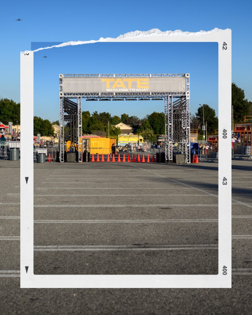 The entrance to the Tate McRae album release party. Past the entrance are fences to guide guests, and in the distance are food trucks.