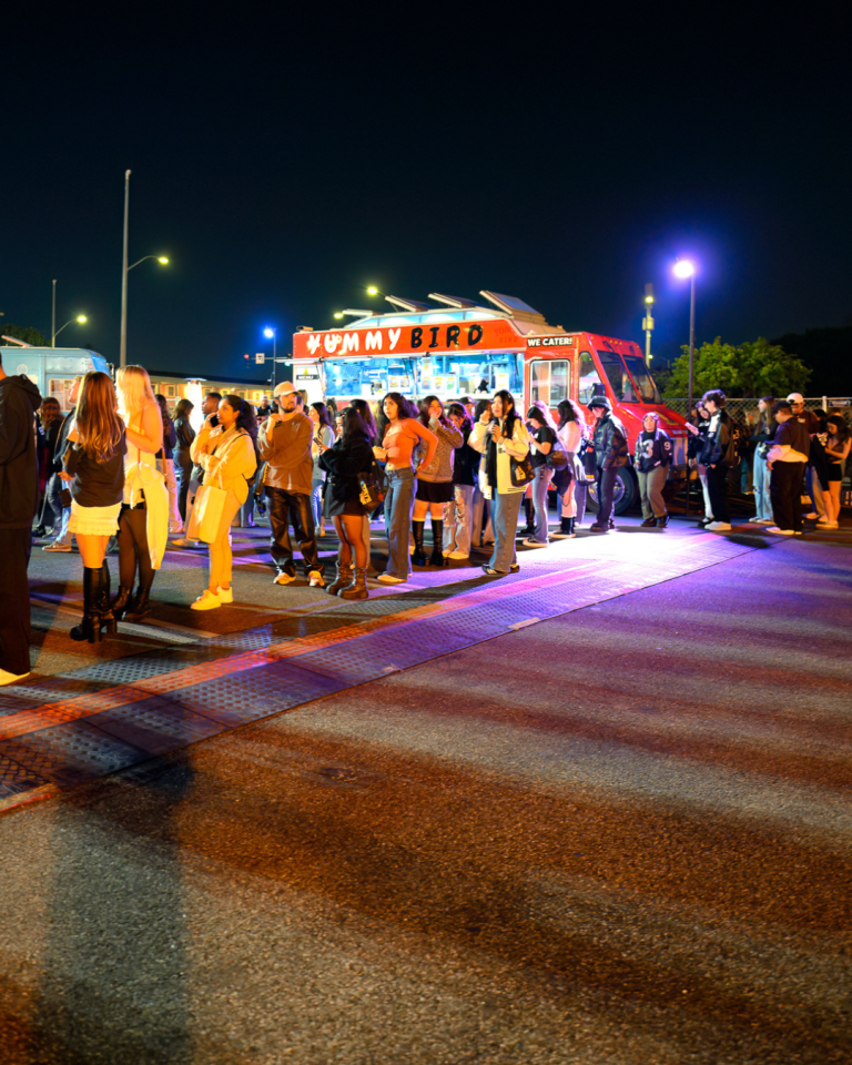 A crowd waits in line for a meal at the catering food trucks servicing Tate McRae's album release party.