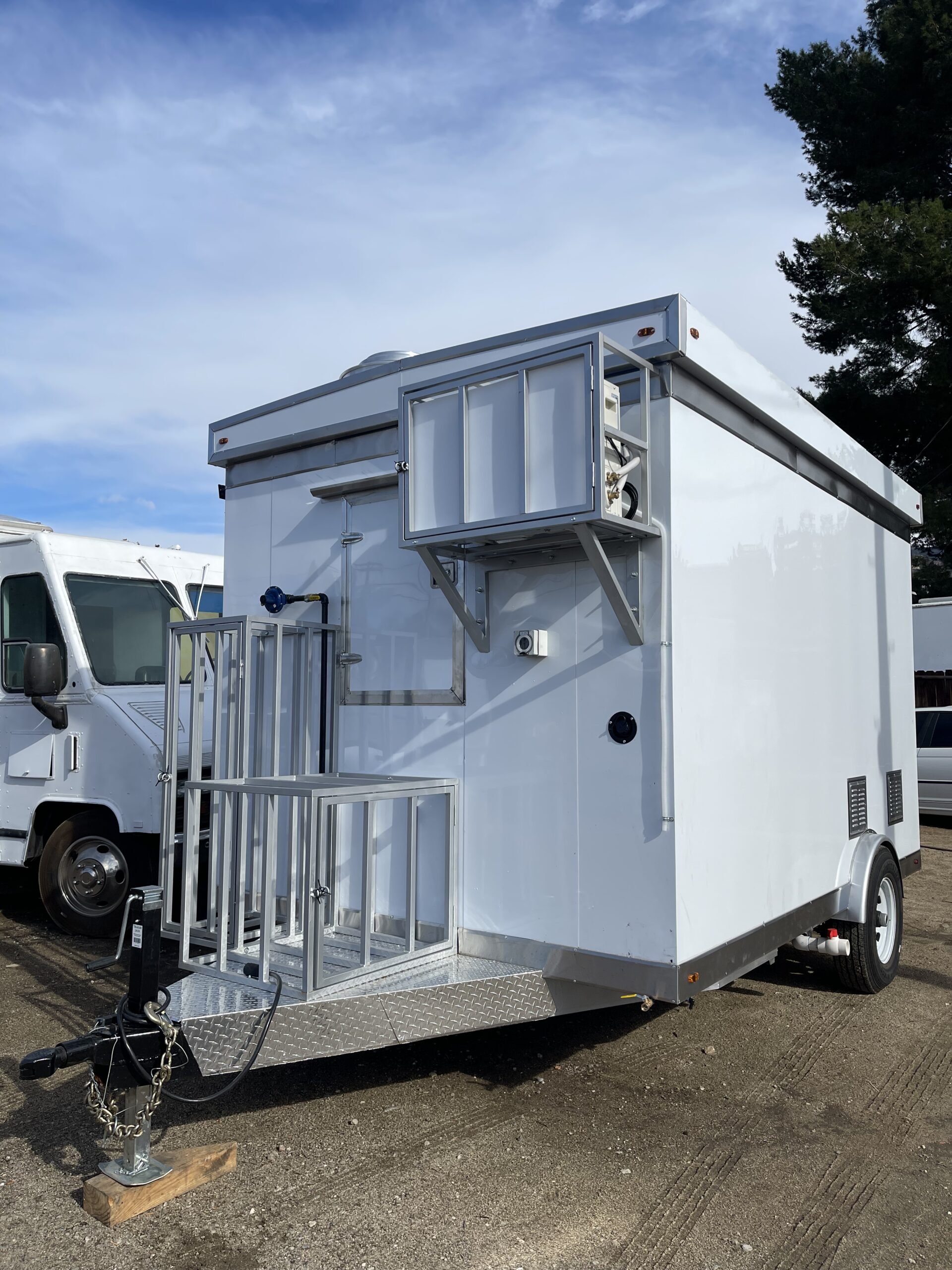 A wide shot of a trailer on dirt ground. The trailer faces slightly to the side and towards the viewer. The sky is cloudy.