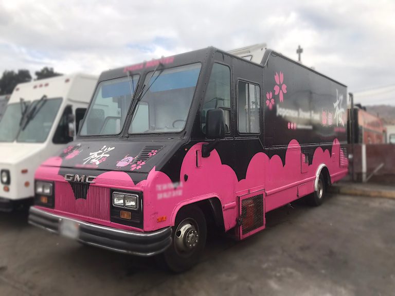 Wide shot of a food truck. Upper half is black, lower half is hot pink.