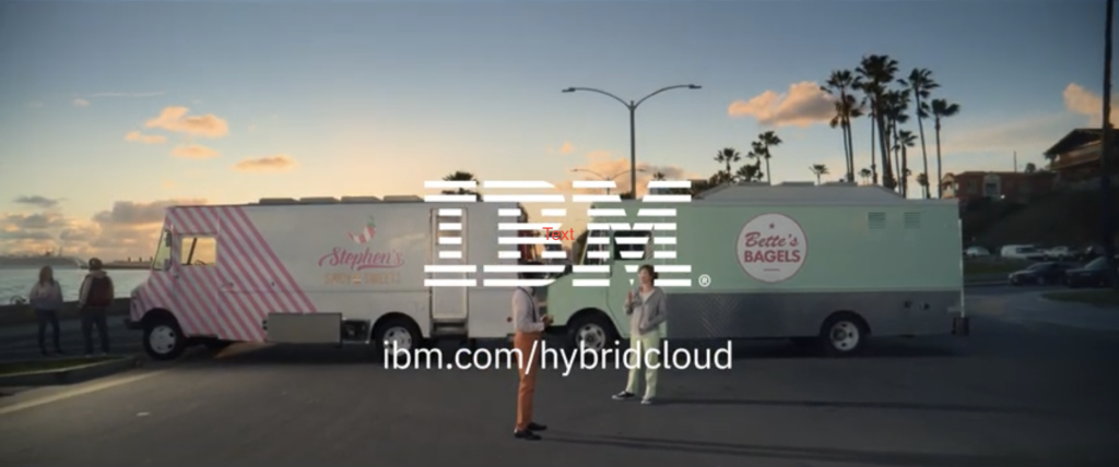 A wide shot on a road at sunset. Two food trucks are parked together, blocking the road for the AD. Standing in front of the food trucks are the drivers discussing. In front of them is the IBM logo, followed by a link to IBM’s hybrid cloud.