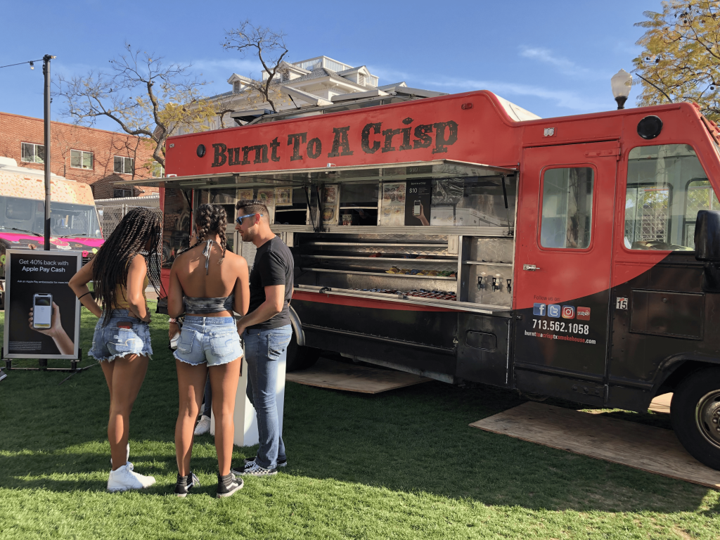 A wide shot of the food truck, Burnt To A Crisp. The truck is red on the upper half and black on the bottom half.